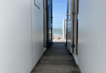 Udsigt fra en strandhytte med åbne døre mod havet i Dishoek, Zeeland, Holland, solrig dag.