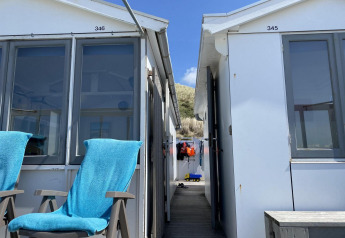 Due sedie blu fuori dalle case sulla spiaggia Dishoek 345 e 346 a Zeeland, Paesi Bassi, sotto il sole.