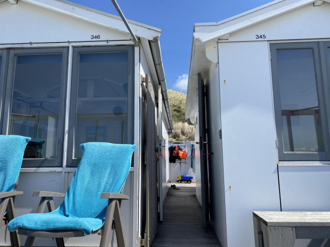 Twee blauwe stoelen bij strandhuisjes Dishoek 345 en 346 in Zeeland, Nederland, onder een blauwe lucht.