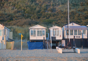 Strandhäuser am Dishoek 345/346 in Zeeland, Niederlande, mit Sand, Dünen und einem Katamaran davor.