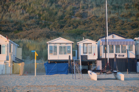 Cabañas de playa en Dishoek 345/346 en Zeeland, Países Bajos, con arena, dunas y un catamarán delante.