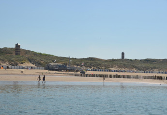 Vista de playa en Beach house 'Dishoek 345/346' en Welcome.in, Zeeland, Países Bajos, con dunas y torres.