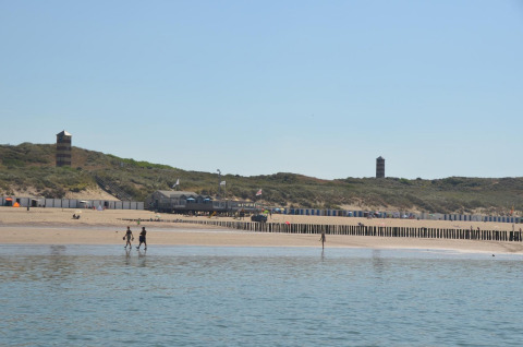 Vista de playa en Beach house 'Dishoek 345/346' en Welcome.in, Zeeland, Países Bajos, con dunas y torres.