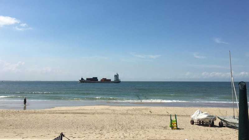 Strandblick vom Beach House 'Dishoek 345/346' mit Sand, Meer, Containerschiff und Booten in Zeeland, Niederlande.