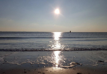 Solnedgang over havet ved Dishoek Beach House i Zeeland, Holland med bløde bølger og roligt vand.