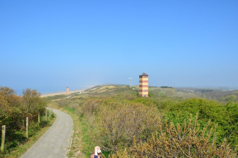 Vista de dunas verdes, camino y dos torres rayadas en la playa de Dishoek, Zelanda, Países Bajos.