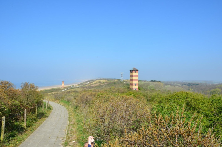 Uitzicht op groene duinen, een pad en twee gekleurde torens bij Dishoek, Zeeland, Nederland.