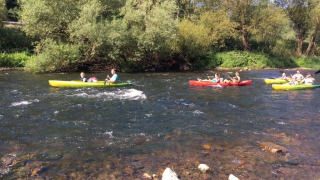 Personas navegando en kayak por un río rodeado de árboles en Camping du Rivage en Diekirch, Luxemburgo.