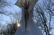 Tienda tipi en Buytenplaets Suydersee, Países Bajos, con luz solar entre los árboles.