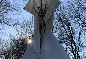 Tipi tent at Buytenplaets Suydersee in the Netherlands with sunlight filtering through trees.