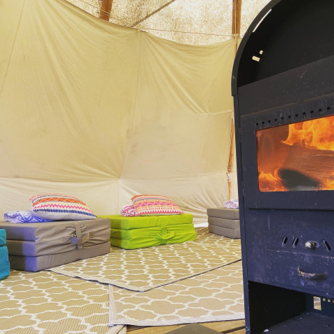Interno di una tenda tipi a Buytenplaets Suydersee, Paesi Bassi, con materassi e stufa a legna.