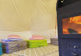 Intérieur d'une tente tipi à Buytenplaets Suydersee, Pays-Bas, avec matelas au sol et poêle à bois.