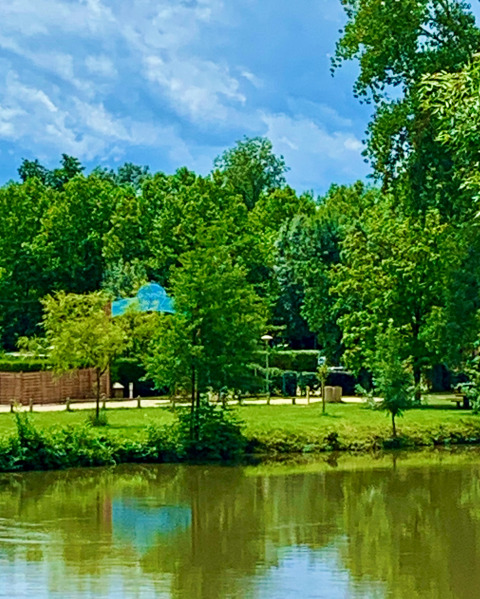 View of the lake and Camping Paradis Aubeterre holiday park surrounded by lush trees in Nouvelle-Aquitaine, France.