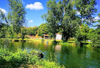 Smuk udsigt over sø og træer ved Camping Paradis Aubeterre, en feriepark i Nouvelle-Aquitaine, Frankrig.