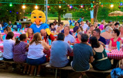 Persone sedute a tavoli lunghi con tovaglie rosse a Camping Paradis Aubeterre, parco vacanze in Francia.