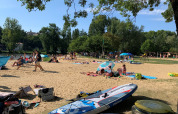Turistas descansan en la playa de arena bajo árboles en Camping Paradis Aubeterre, Nouvelle-Aquitaine, Francia.