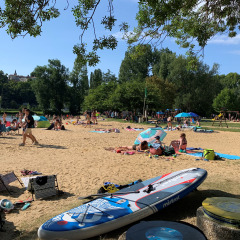 Turistas descansan en la playa de arena bajo árboles en Camping Paradis Aubeterre, Nouvelle-Aquitaine, Francia.