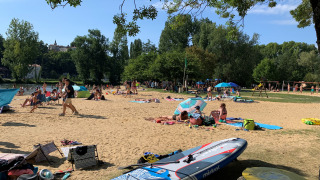Turistas descansan en la playa de arena bajo árboles en Camping Paradis Aubeterre, Nouvelle-Aquitaine, Francia.