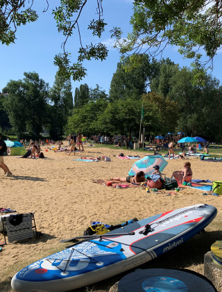 Ferieparkgæster slapper af på sandstrand med paddleboard på Camping Paradis Aubeterre, Nouvelle-Aquitaine.
