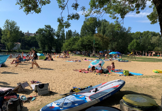 Holidaymakers relaxing on the sandy beach beside trees at Camping Paradis Aubeterre in Nouvelle-Aquitaine, France.