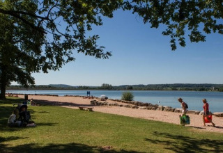 Persone trascorrono una giornata di sole al lago presso Camping du Lac, parco vacanze in Grand Est, Francia.
