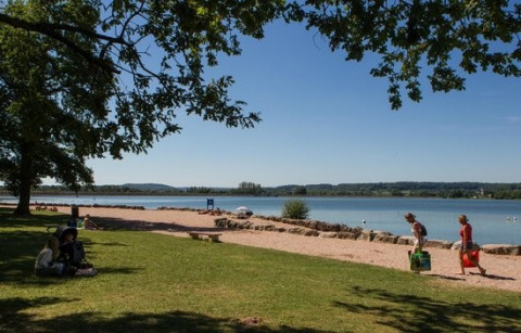 Folk nyder en solrig dag ved søen på Camping du Lac, en feriepark i Grand Est-regionen i Frankrig.