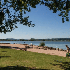 People enjoy a sunny day by the lake at Camping du Lac, a holiday park in the Grand Est region of France.