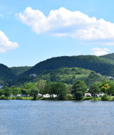 View of the lake, green hills, and small houses near Villegusien le Lac in Grand Est, France, on a sunny day.