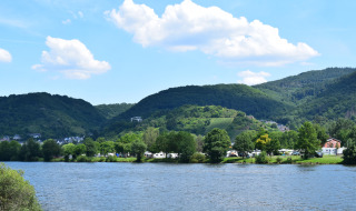 View of the lake, green hills, and small houses near Villegusien le Lac in Grand Est, France, on a sunny day.