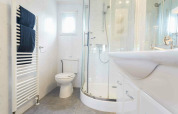 Modernes Bad in einer Hütte mit Dusche, weißer Toilette, Waschbecken und beheiztem Handtuchhalter.