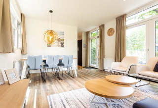 Alojamiento glamping luminoso con diseño moderno, mesa de comedor, sillones cómodos y grandes ventanales.