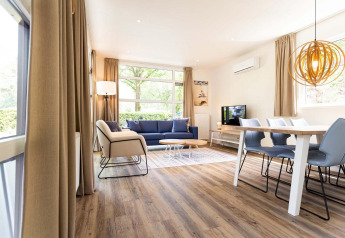 Moderne glamping bolig med lyst interiør, trægulv, spisebord, komfortabel sofa og store vinduer.