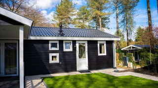 Heuvelrug Cottage met hottub aan De Thijmse Berg, Nederland, omringd door bomen en een groene grasmat.