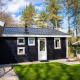 Sort Heuvelrug Cottage med varmt kar på De Thijmse Berg, omgivet af grønne træer og græsplæne i Holland.