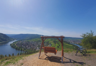 Vue panoramique près de Kröv, Allemagne, avec une balançoire, un vélo et la rivière Moselle en contrebas.
