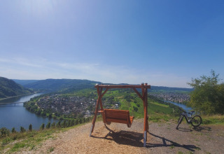 Vista panoramica vicino a Kröv, Germania, con una panchina a dondolo, bicicletta e il fiume Mosella.