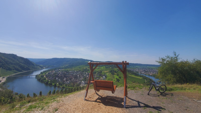 Vue panoramique près de Kröv, Allemagne, avec une balançoire, un vélo et la rivière Moselle en contrebas.