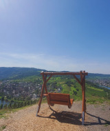 Vista panorámica cerca de Kröv, Alemania, con un columpio, una bicicleta y el río Mosela al fondo.