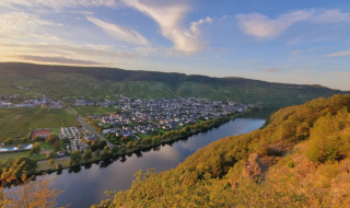 Vista del río y el pueblo de Kröv, rodeado de colinas y viñedos en Renania-Palatinado, Alemania, al atardecer.