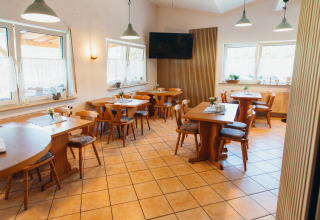 Sala da pranzo con mobili in legno e grandi finestre al Paradies Camp, villaggio turistico in Renania-Palatinato, Germania.