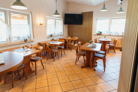 Sala da pranzo con mobili in legno e grandi finestre al Paradies Camp, villaggio turistico in Renania-Palatinato, Germania.
