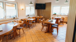 Comedor con muebles de madera y grandes ventanas en Paradies Camp, parque vacacional en Renania-Palatinado, Alemania.