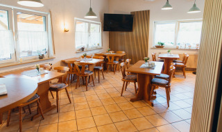 Comedor con muebles de madera y grandes ventanas en Paradies Camp, parque vacacional en Renania-Palatinado, Alemania.