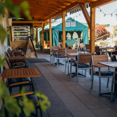 Zona de comedor exterior techada en Paradies Camp, Renania-Palatinado, Alemania, con mesas y sillas de madera.