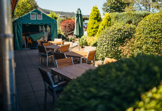 Udendørs spiseområde på Paradies Camp feriepark i Rhinland-Pfalz, Tyskland, omgivet af frodige buske.