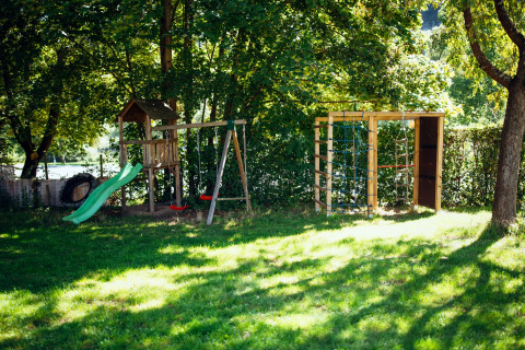 Spielplatz mit Rutsche und Schaukeln im Paradies Camp, einem Ferienpark in Rheinland-Pfalz, Deutschland.
