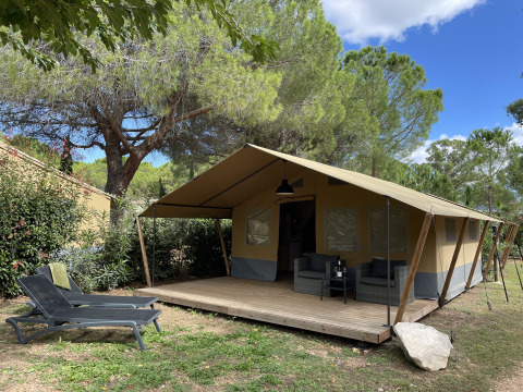 Safari-Zelt auf Camping le Mas de Mourgues in Frankreich mit Holzterrasse und Gartenmöbeln.
