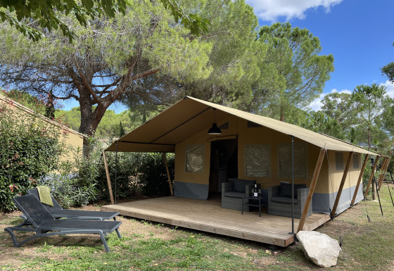 Safari-Zelt auf Camping le Mas de Mourgues in Frankreich mit Holzterrasse und Gartenmöbeln.