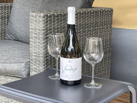 Fles witte wijn en twee wijnglazen op een tafeltje in een safaritent bij Camping le Mas de Mourgues, Frankrijk.