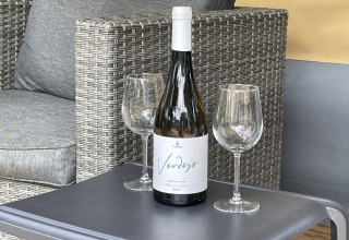 Fles witte wijn en twee wijnglazen op een tafeltje in een safaritent bij Camping le Mas de Mourgues, Frankrijk.